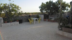 A patio with a stone floor, yellow chairs, and a table. - VILLA GELSOMINO IMMERSED IN THE NATURE SALENTO S. M.DI LEUCA  (corsano)