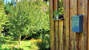 A wooden cabin with a stone pathway leading to the entrance, surrounded by lush greenery. - Chiemgau, charming chalet with private garden , relax in nature (Siegsdorf)