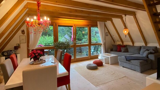 An attic room with a dining table, chairs, a sofa, and a chandelier. - Chiemgau, charming chalet with private garden , relax in nature (Siegsdorf)