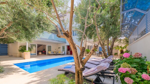 Zona de piscina con sillas de descanso, una alberca y follaje circundante.