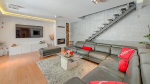 Una sala moderna con un sofá gris, una mesa de centro y una escalera.