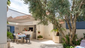 Un patio con piscina, mobiliario exterior y plantas en macetas.