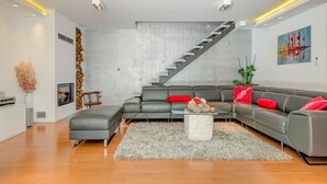 Una sala de estar moderna con un sofá gris, cojines rojos, una mesa de centro blanca y una escalera.