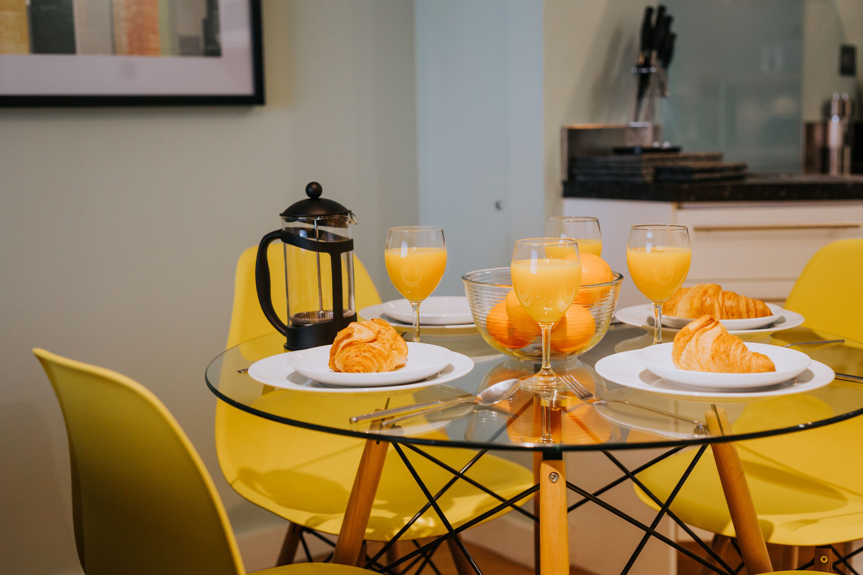 Ein Frühstückstisch mit Croissants, Orangensaft und einer Kaffeekanne.