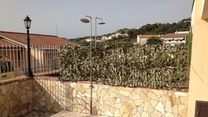 A courtyard with a stone wall, a metal fence, and a tiled floor. - House with garden, gazebo, barbecue, pizza oven, and a view of Isola Cirella (Diamante)