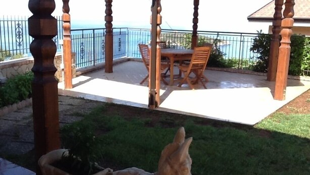 A wooden gazebo with a table and chairs, overlooking a body of water. - House with garden, gazebo, barbecue, pizza oven, and a view of Isola Cirella (Diamante)