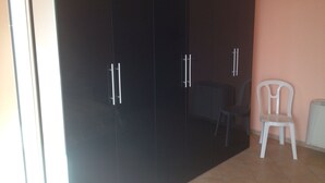 A room with a large dark wardrobe, a white chair, and a small table. - House with garden, gazebo, barbecue, pizza oven, and a view of Isola Cirella (Diamante)