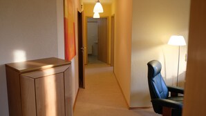 A hallway with a wooden cabinet, a black leather chair, and a floor lamp. - Apartment in a green idyll on the edge of Chemnitz (Chemnitz)