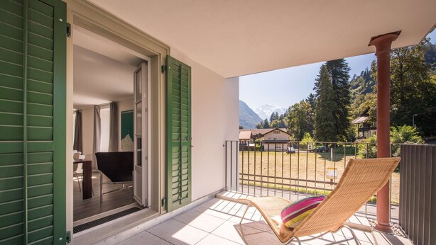 A balcony with a wicker chair and a view of a mountain landscape. - Spacious and central apartment with terrace (Matten bei Interlaken)