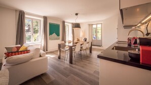 A modern hotel room with a sofa, dining table, chairs, and a kitchen area. - Spacious and central apartment with terrace (Matten bei Interlaken)