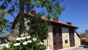 Un edificio de piedra con tejido rojo y un pequeño jardín con flores blancas.
