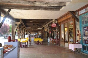 Un café en plein air avec des poutres en bois et des tables jaunes.