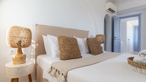 Een keurig opgemaakt slaapkamer met een bed, kussens, een bedlampje en een mand.