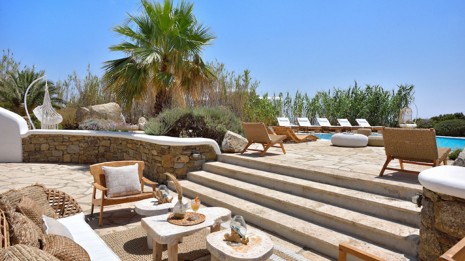 A poolside area with lounge chairs, a stone staircase, and a view of the pool.