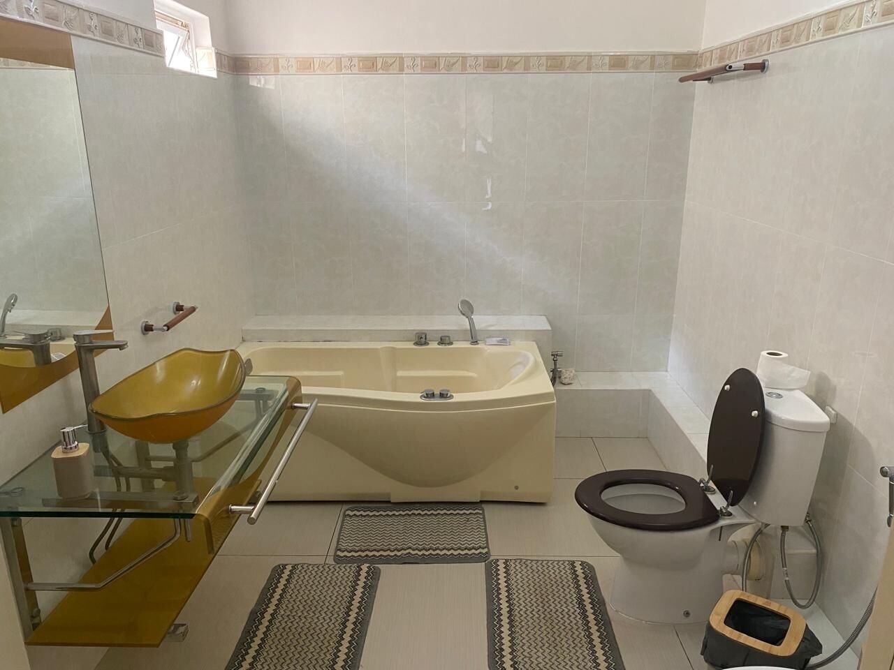 A bathroom with a glass sink, a bathtub, a toilet, and a shower area.