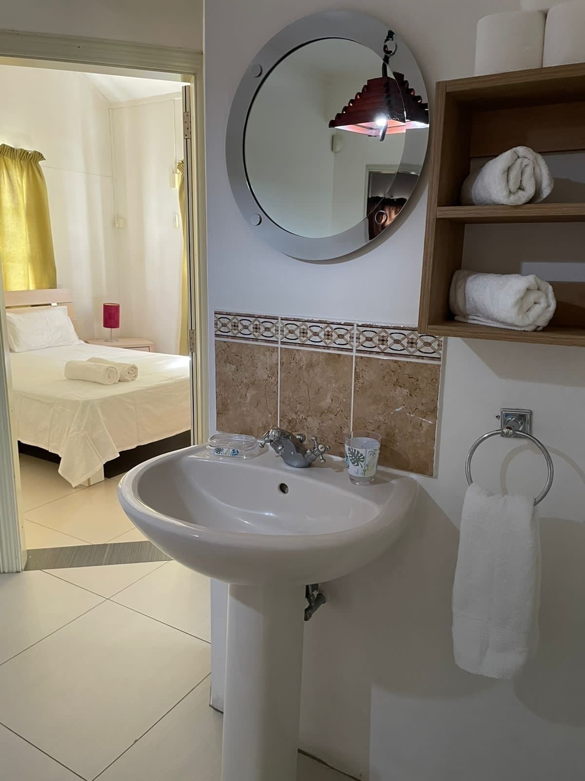 A hotel bathroom with a sink, mirror, and towel rack.