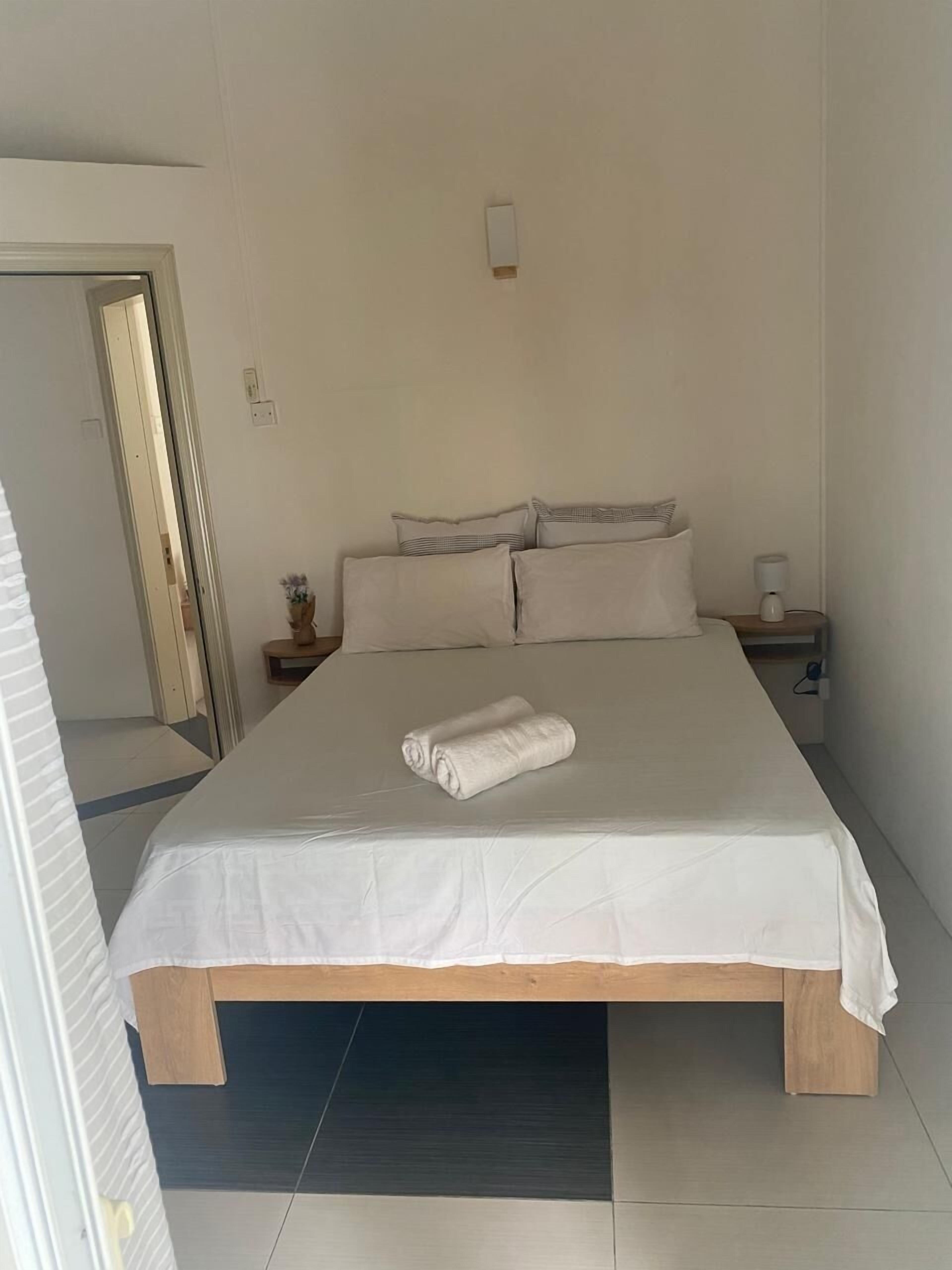 Une chambre à coucher avec un lit, des oreillers, une table de chevet et une lampe fixée au mur.