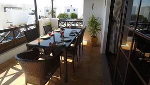 A terrace with a table set for dining, chairs, a potted plant, and a view of buildings in the background. - Fabulous Detached Villa in Premier Location, Full Air Con, Heated Pool, Wi-Fi + (Puerto del Carmen)
