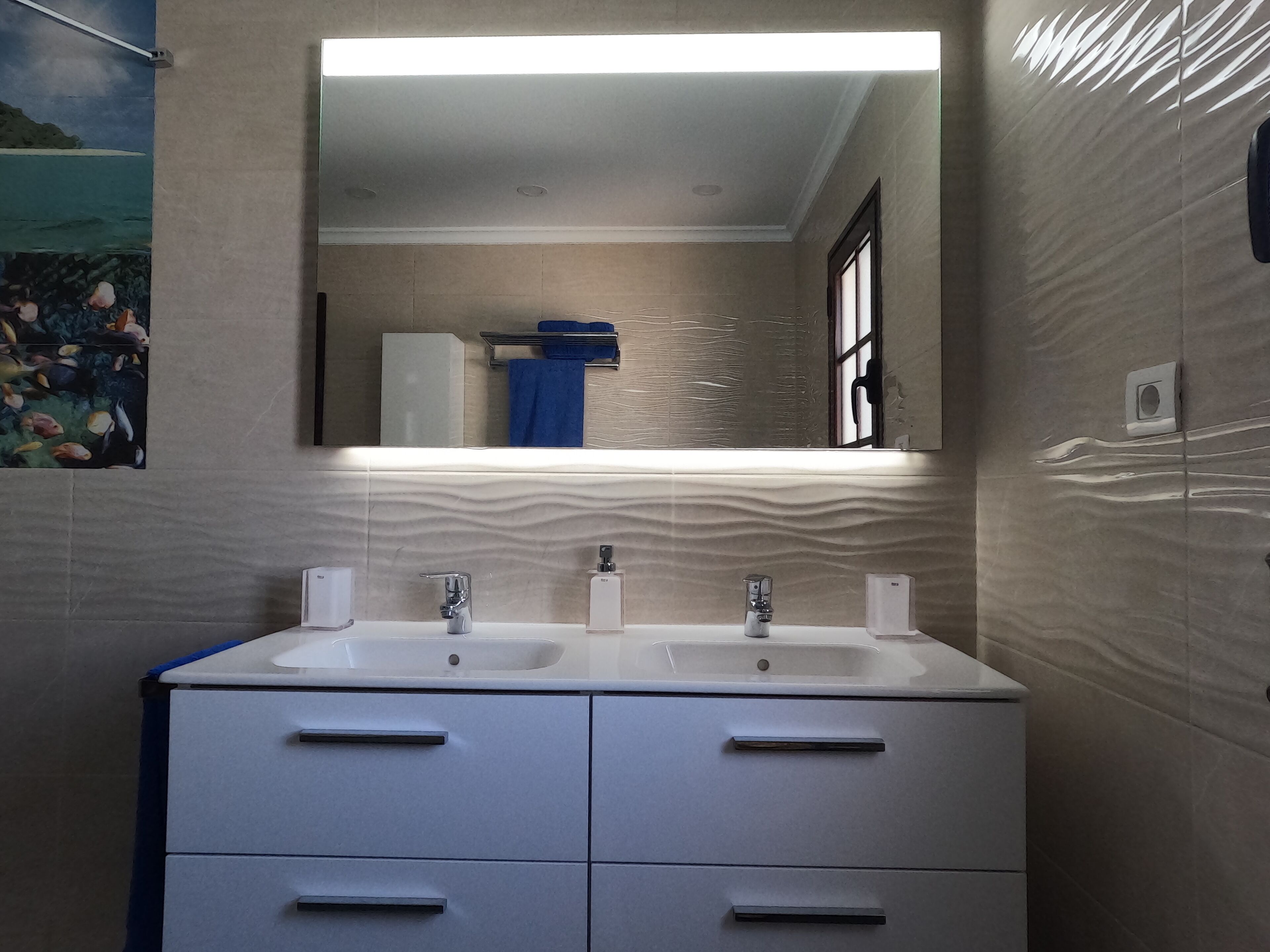 A bathroom with two sinks, a mirror, and a towel rack.