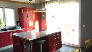 A modern kitchen with red cabinets, a large island, and pendant lights. - Contemporary cottage between Ubaye and Durance overlooking the lake of Serre Ponçon 2 (Le Sauze-Du-Lac)