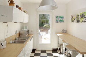 A modern kitchen with a checkered floor, a microwave, a sink, and a large window.