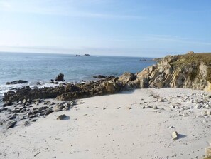 A rocky beach with a clear view of the ocean and distant landforms.