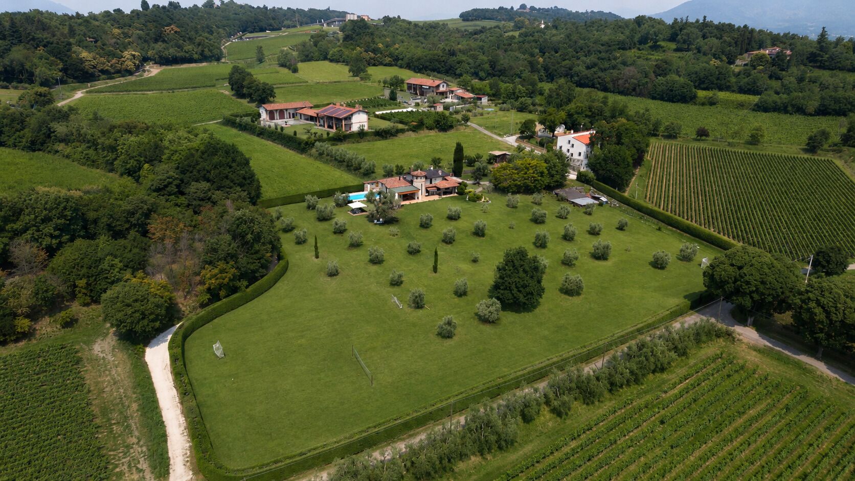 Una grande tenuta con diversi edifici, ampi prati verdi e un prato curato.