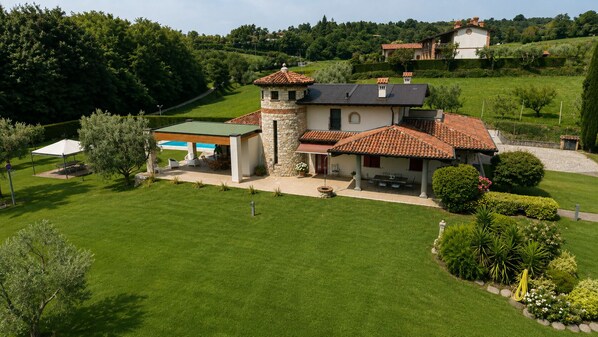 Una villa con una torre de piedra, un porche cubierto y un césped cuidado.
