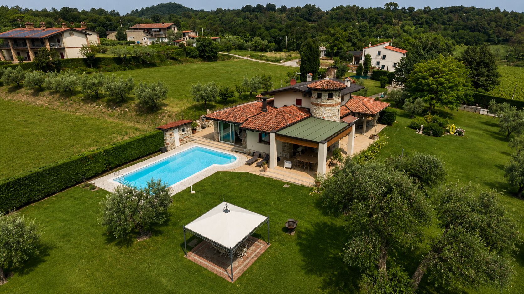 Un'ampia casa con piscina, area salotto esterna coperta e prato curato.