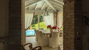 A dining area with a table and chairs, a hanging light fixture, and a view of a swimming pool.