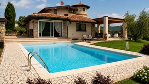 A house with a swimming pool, a covered patio, and a stone pathway.