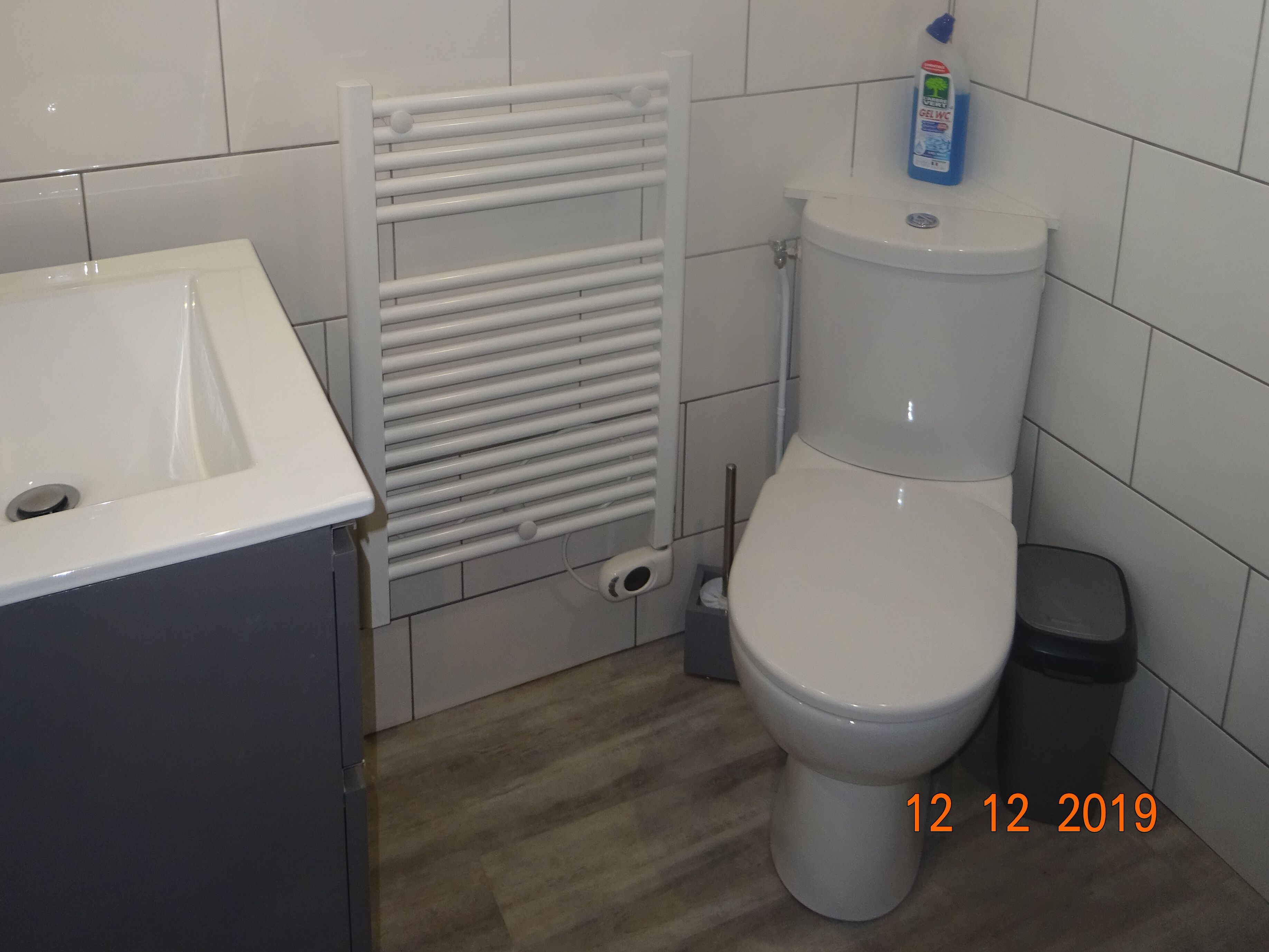 A bathroom with a toilet, a white sink, and a towel rack.