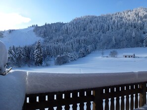 Un paysage enneigé, avec une clôture en bois au premier plan et un petit bâtiment à l’horizon.