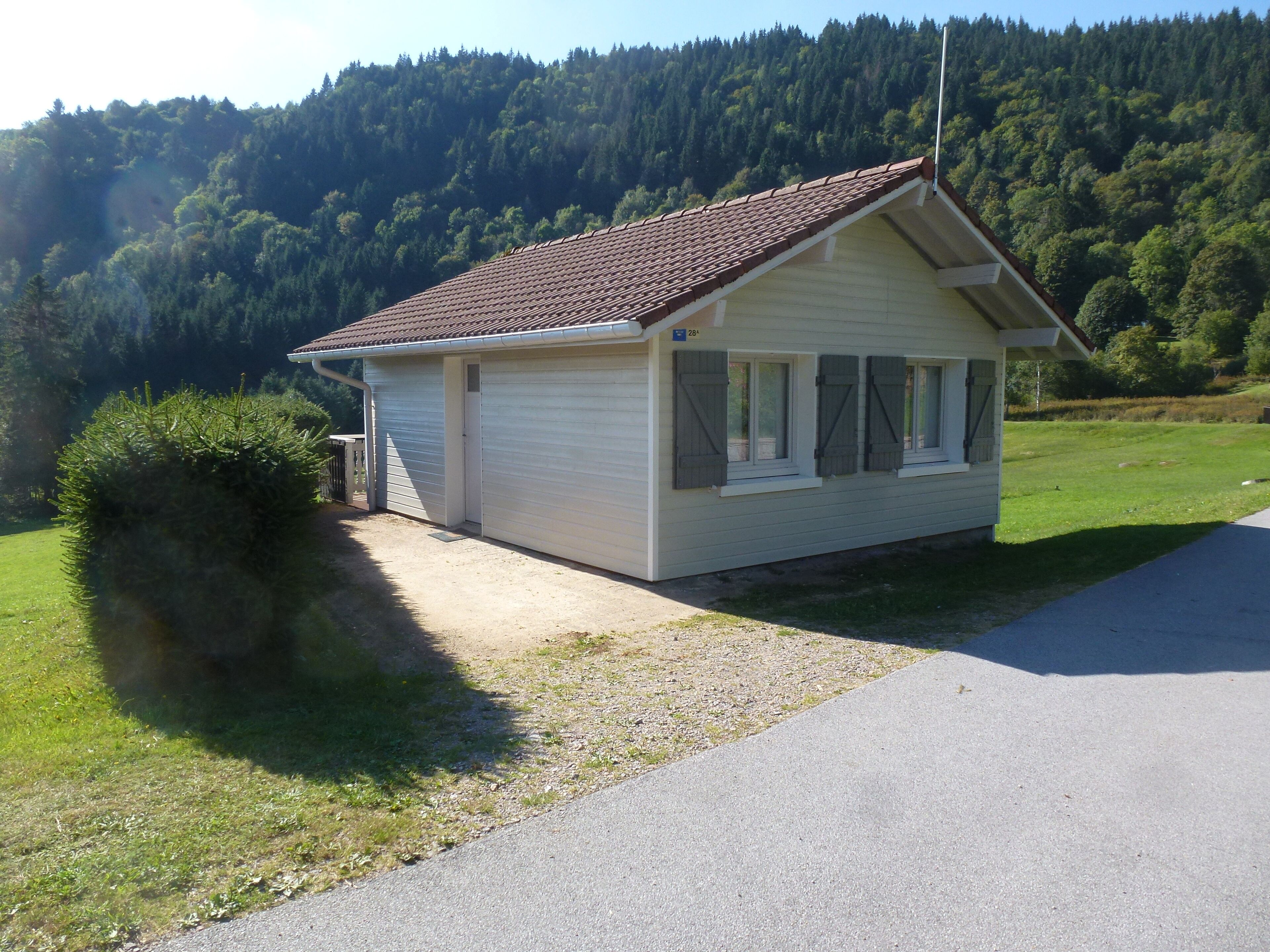 A small, single-story building with a sloped roof, a garage, and a paved driveway.