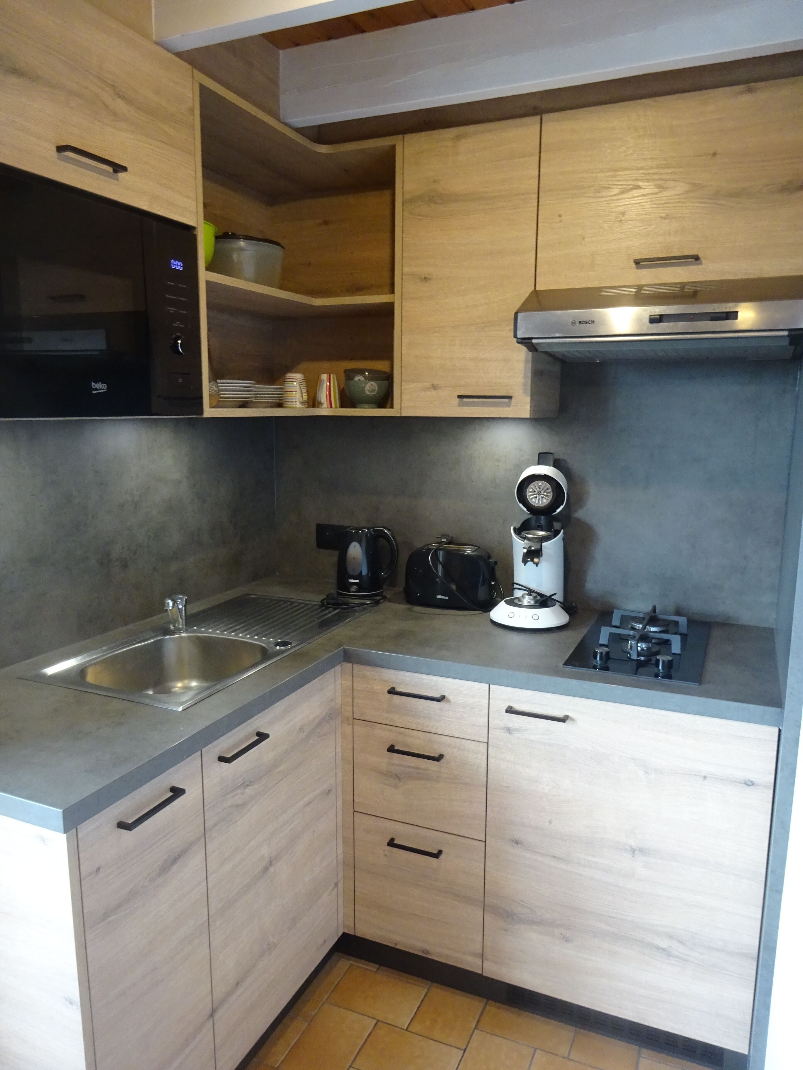 A compact kitchen with a sink, stove, toaster, and microwave.