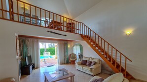 A spacious living area with a staircase, a glass coffee table, a sofa, and a television. - Beautiful villa with private pool & playground near Lagos & the beach (Vale da Lama)