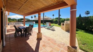 A covered patio with a pool, outdoor seating, and a view of a house in the background. - Beautiful villa with private pool & playground near Lagos & the beach (Vale da Lama)