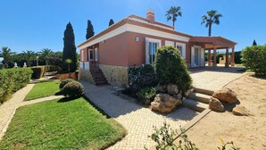 A house with a stone facade, a covered porch, and a well-maintained garden with grass and shrubs. - Beautiful villa with private pool & playground near Lagos & the beach (Vale da Lama)