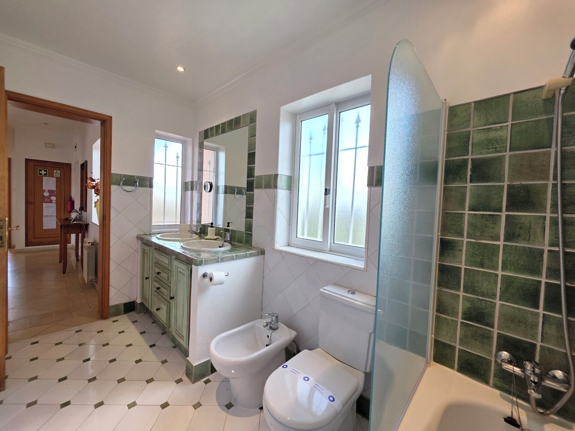 A bathroom with two sinks, a bidet, a toilet, and a glass-enclosed shower.