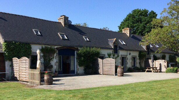 A traditional stone building with a dark tiled roof, a central entrance with a blue door, and a gravel driveway. - LONGERE WITH COVERED AND HEATED SWIMMING POOL FOR 20 PEOPLE (EVELLYS)
