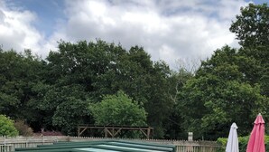 A rooftop pool area with lounge chairs and umbrellas. - LONGERE WITH COVERED AND HEATED SWIMMING POOL FOR 20 PEOPLE (EVELLYS)