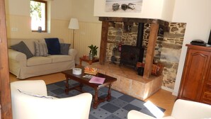 A cozy living room with a stone fireplace, a sofa, and a coffee table. - LONGERE WITH COVERED AND HEATED SWIMMING POOL FOR 20 PEOPLE (EVELLYS)