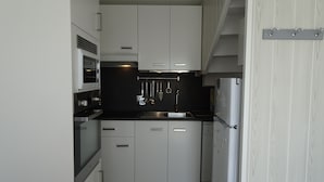 Una cucina moderna con mobili bianchi, un piano di lavoro nero e elettrodomestici in acciaio inossidabile.