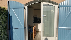 Un patio con tavolo e sedie, un cancello blu e vista su una stanza con angolo cottura.
