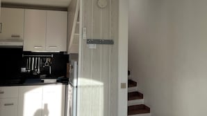 Una cucina moderna con mobili bianchi, forno integrato e ventilatore a soffitto.