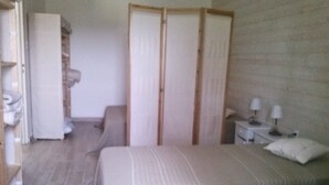A bedroom with a bed, a nightstand with a lamp, a wardrobe, and a chair. -  Lodgings in Vannes (Plescop)