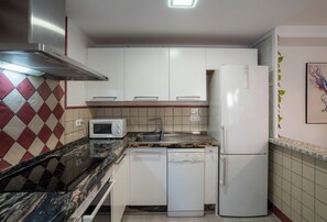 A kitchen with white cabinets, a microwave, a dishwasher, and a refrigerator.