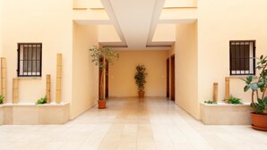 A corridor with tiled flooring, potted plants, and windows with bars. - ATTRACTIVE APARTMENT IN COSTA BRAVA (Tossa de Mar)