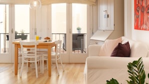 A bright living room with a white sofa, a dining table with chairs, and a kitchen area with cabinets. - ATTRACTIVE APARTMENT IN COSTA BRAVA (Tossa de Mar)
