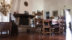 A rustic interior with a fireplace, wooden furniture, and a tiled floor.